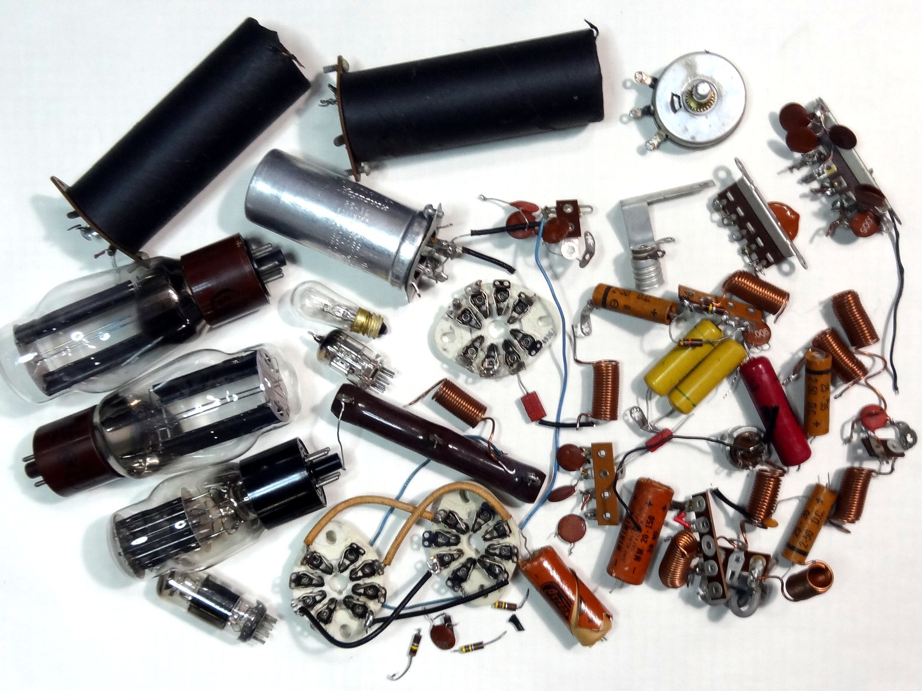 Figure 5 — The yield of one thorough restoration: every capacitor, resistor, socket, potentiometer and valve removed from a single DX-100, laid out on the bench.