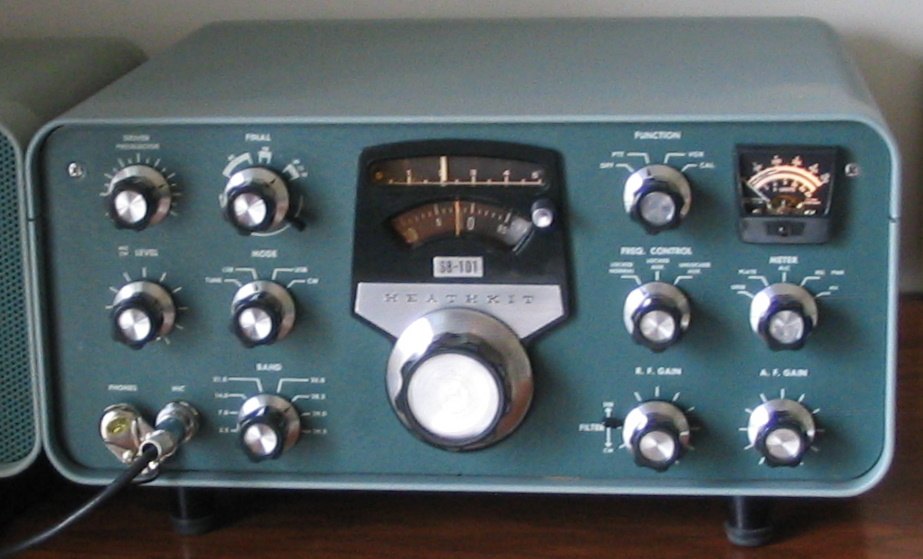 Figure 4 — An SB-101 transceiver of 1967–1970: grey cabinet, green panel, the round kilohertz dial under the slide-rule scale, and the meter and function switches to the right. The SB transceivers packed the …