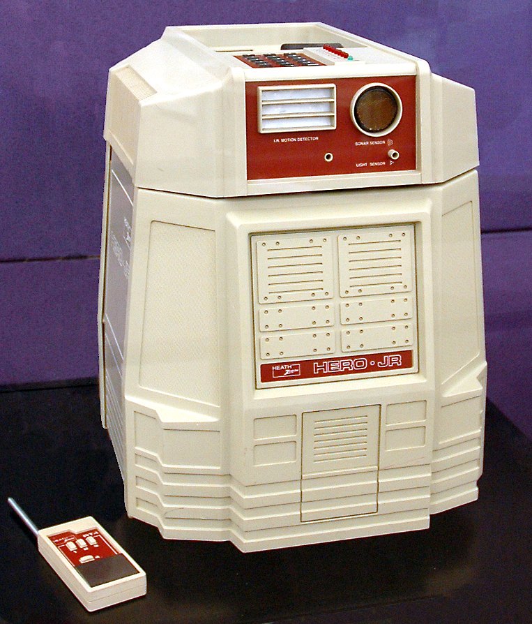 Figure 5 — A surviving HERO Jr with its RF remote control. The red face panel carries the infrared motion detector, the sonar sensor and the light sensor; the keypad is on top of the head.