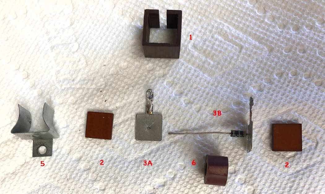 Figure 4 — The same rectifier taken apart: phenolic case, two phenolic end plates, two terminal end plates and the stack of selenium-coated plates. A 1N4004 fits inside the empty case, which keeps the restora…